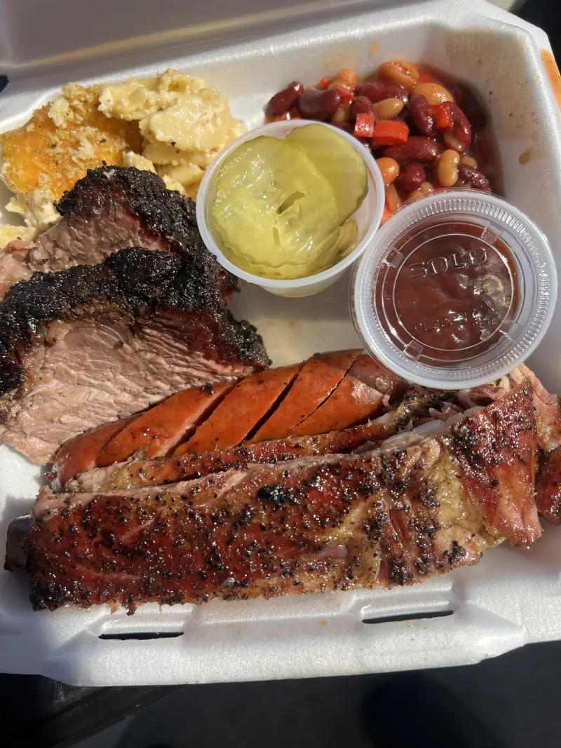 Three-meat BBQ catering plate with brisket, ribs, and classic sides