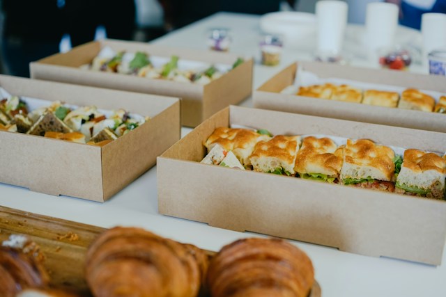 Cardboard catering trays of sandwiches and filled rolls set out on a table