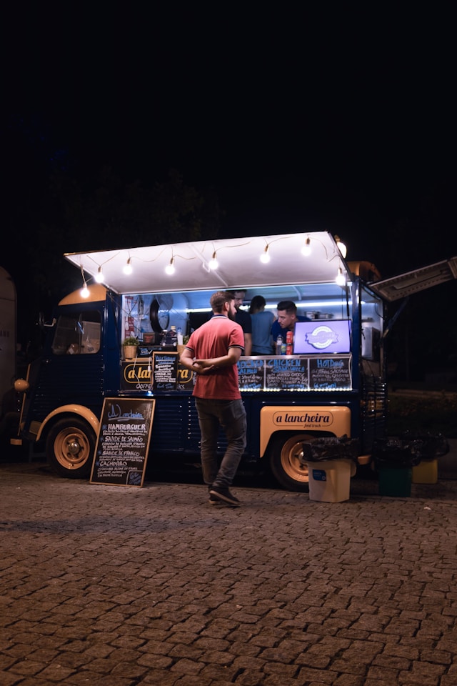 Guest ordering from a food truck lit by string lights at night